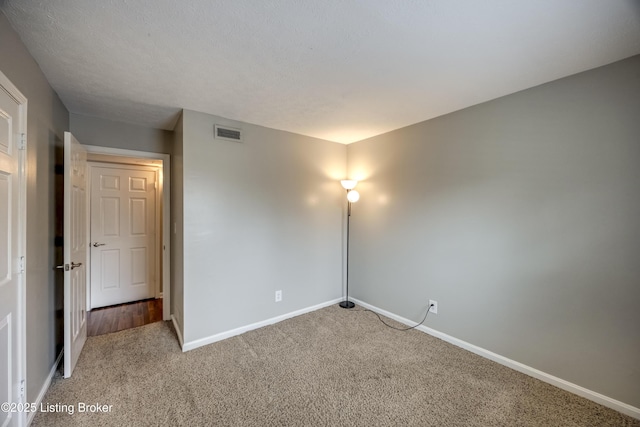 unfurnished room featuring carpet floors, visible vents, and baseboards