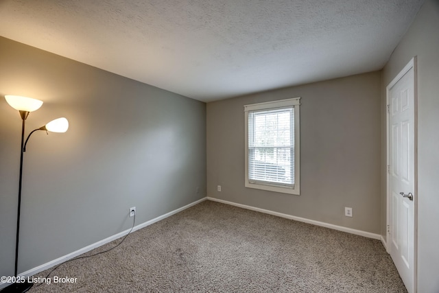 carpeted spare room with a textured ceiling and baseboards