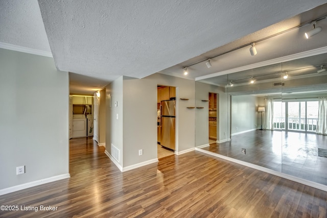 unfurnished room featuring a textured ceiling, visible vents, wood finished floors, and ornamental molding