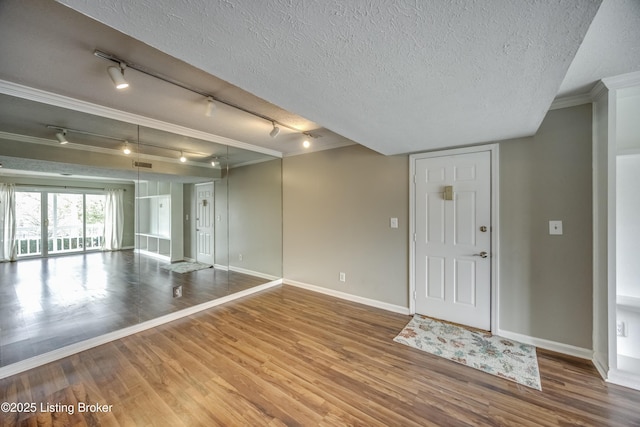 interior space featuring a textured ceiling, baseboards, and wood finished floors