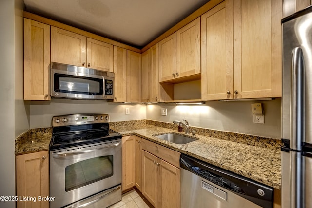 kitchen featuring appliances with stainless steel finishes, light tile patterned floors, a sink, and light stone countertops