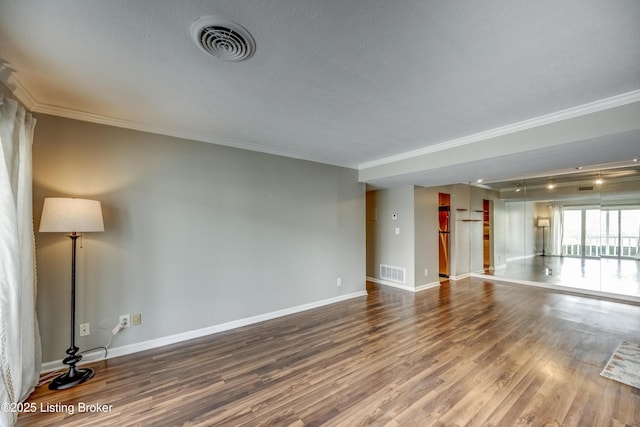 unfurnished room with ornamental molding, wood finished floors, visible vents, and baseboards