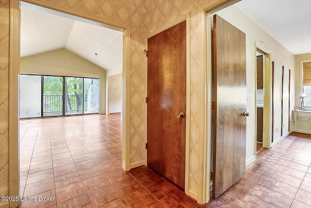 corridor with lofted ceiling and baseboards