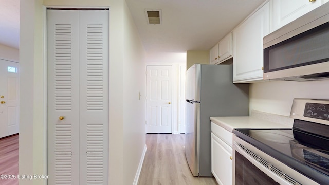 kitchen featuring visible vents, stainless steel appliances, white cabinets, light wood finished floors, and light countertops