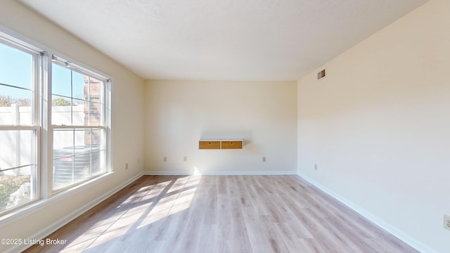 spare room featuring visible vents, baseboards, and light wood finished floors