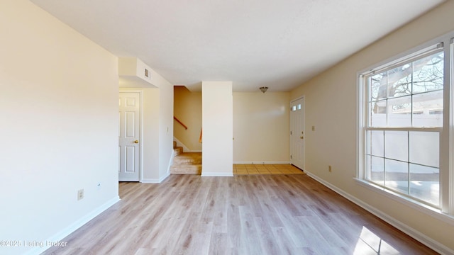 spare room featuring visible vents, baseboards, stairs, and light wood finished floors