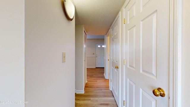 corridor with baseboards and light wood-style flooring