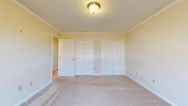 unfurnished bedroom featuring light carpet, baseboards, two closets, and ornamental molding