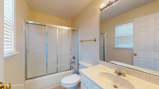 bathroom featuring toilet, vanity, and shower / bath combination with glass door