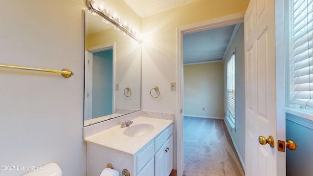 bathroom with toilet, vanity, and baseboards