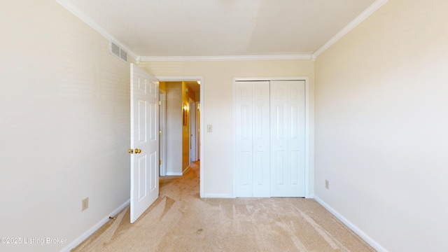 unfurnished bedroom with visible vents, baseboards, light colored carpet, ornamental molding, and a closet