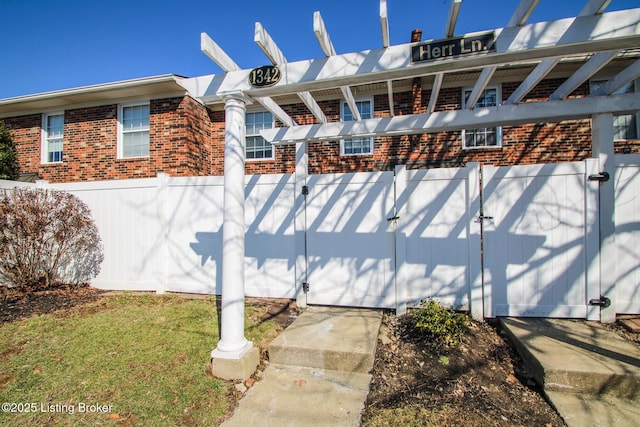 exterior space featuring a gate, fence, and brick siding