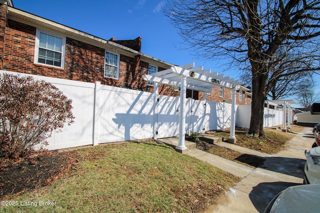 view of side of property with brick siding, a fenced backyard, a lawn, and a pergola