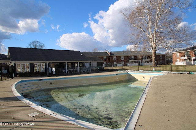 community pool with a patio area and fence