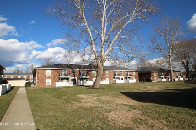 rear view of property with brick siding and a lawn