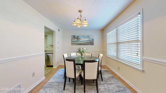 dining area with visible vents, baseboards, a notable chandelier, and light wood-style flooring