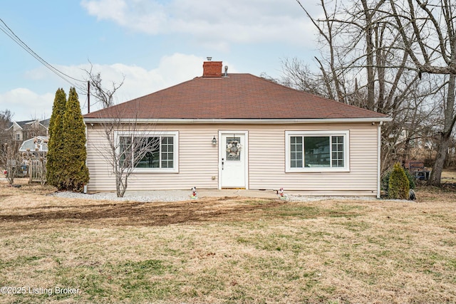 view of front of house featuring a shingled roof, a chimney, and a front yard