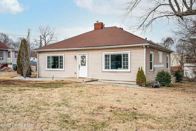 bungalow-style home with roof with shingles, a chimney, and a front lawn