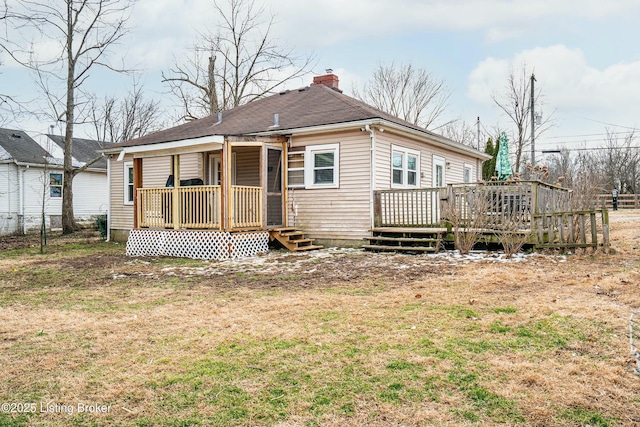 rear view of property with roof with shingles, a chimney, a deck, and a yard