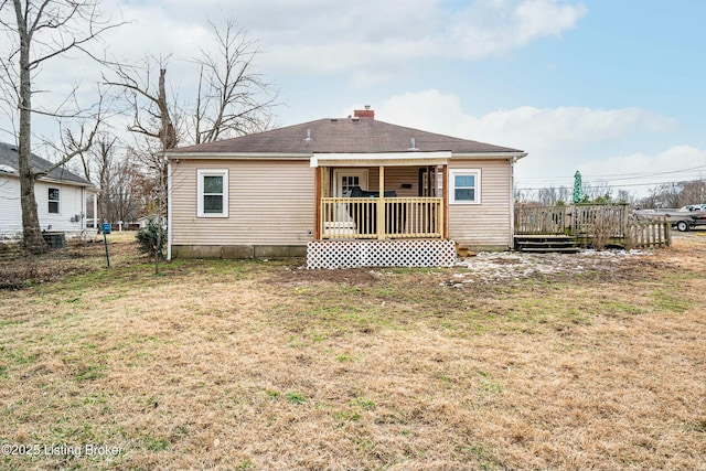 back of property with a chimney, fence, a deck, and a yard