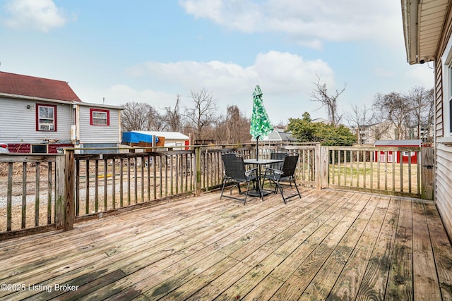 deck featuring a storage unit, an outdoor structure, and outdoor dining space