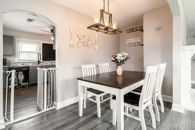 dining room with arched walkways, ceiling fan, dark wood finished floors, and baseboards