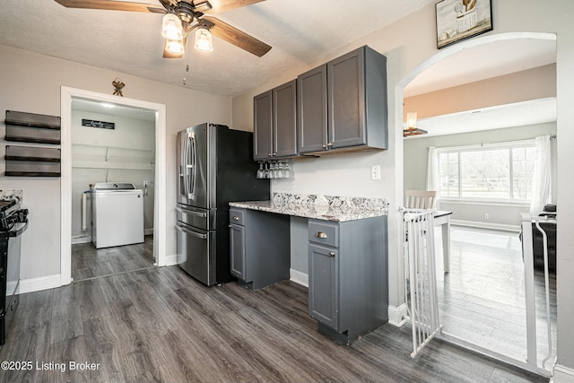 kitchen with baseboards, stainless steel fridge, washer / clothes dryer, and dark wood-type flooring