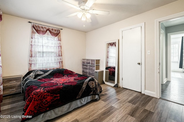 bedroom with dark wood-type flooring, ceiling fan, and baseboards