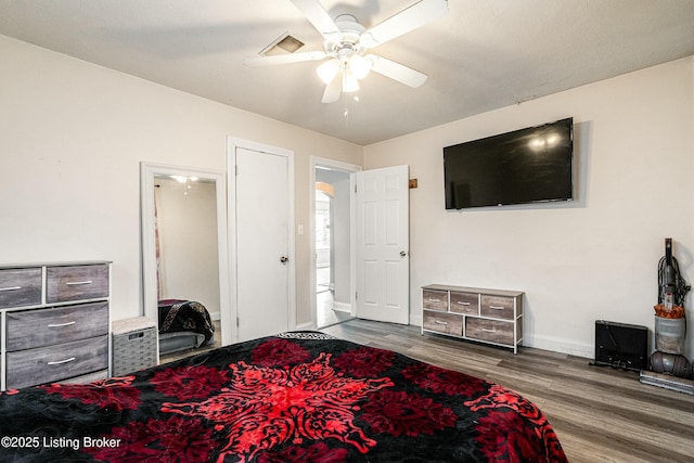 bedroom with baseboards, visible vents, a ceiling fan, and dark wood-type flooring