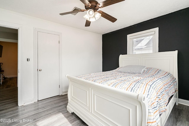 bedroom with a textured ceiling, ceiling fan, wood finished floors, and baseboards