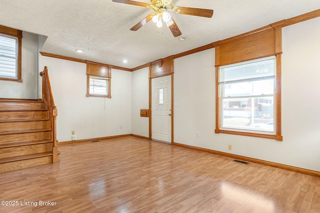 spare room with visible vents, light wood-style flooring, a textured ceiling, baseboards, and stairs