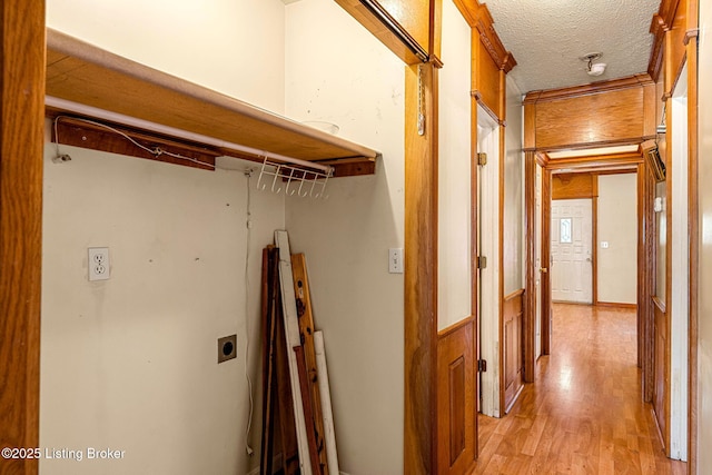 corridor with a textured ceiling and light wood finished floors