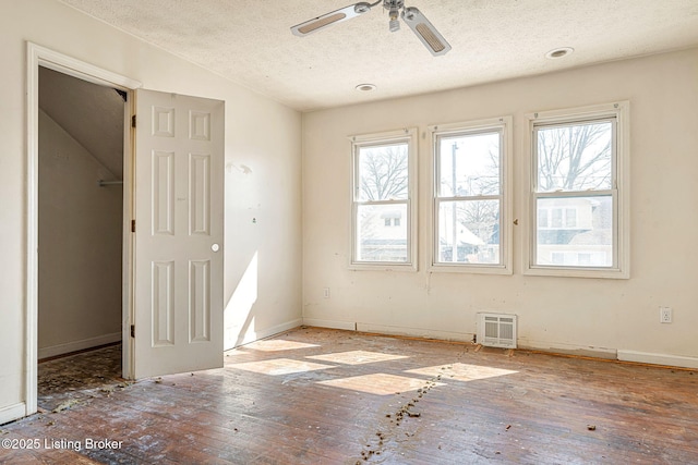 empty room featuring a ceiling fan, baseboards, a textured ceiling, and hardwood / wood-style floors