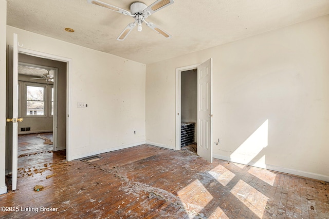 unfurnished room featuring a ceiling fan, visible vents, and baseboards