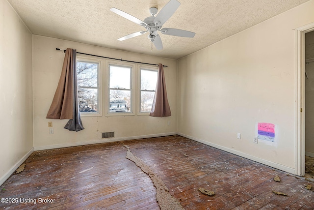 spare room featuring visible vents, ceiling fan, hardwood / wood-style flooring, and baseboards