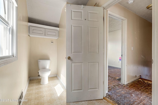 bathroom with a textured ceiling, baseboards, toilet, and tile patterned floors