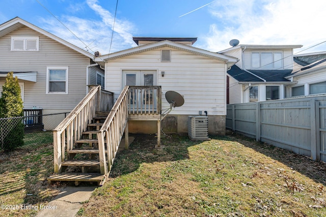 back of property featuring a yard, central AC, french doors, and a fenced backyard