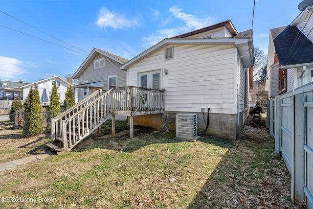 back of house with central air condition unit, a lawn, stairway, fence, and a wooden deck