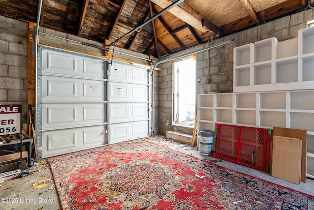 garage featuring wooden ceiling and concrete block wall