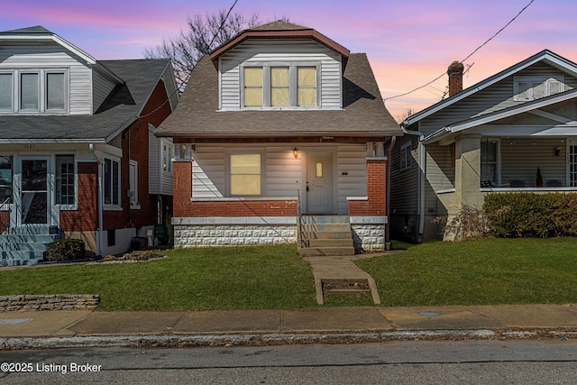 bungalow-style house featuring brick siding, a shingled roof, and a front yard