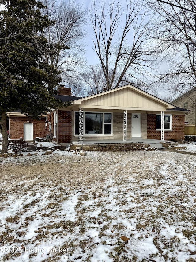 view of front facade featuring covered porch, brick siding, and a chimney