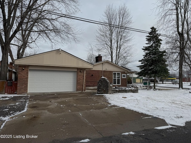 view of front of home with driveway, brick siding, a chimney, and an attached garage