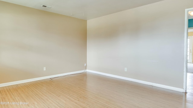 empty room featuring light wood-type flooring, visible vents, and baseboards