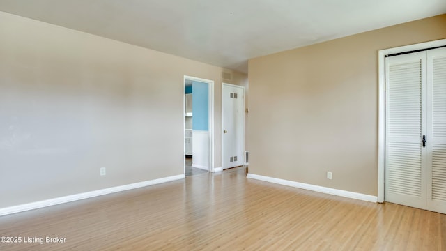 unfurnished bedroom with a closet, light wood-type flooring, visible vents, and baseboards