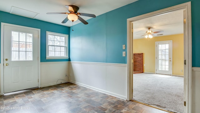 spare room featuring carpet, attic access, stone finish flooring, ceiling fan, and baseboards