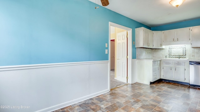 kitchen with baseboards, dishwasher, stone finish flooring, light countertops, and backsplash