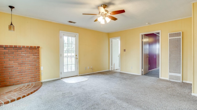 unfurnished living room with carpet floors, visible vents, a ceiling fan, ornamental molding, and a heating unit