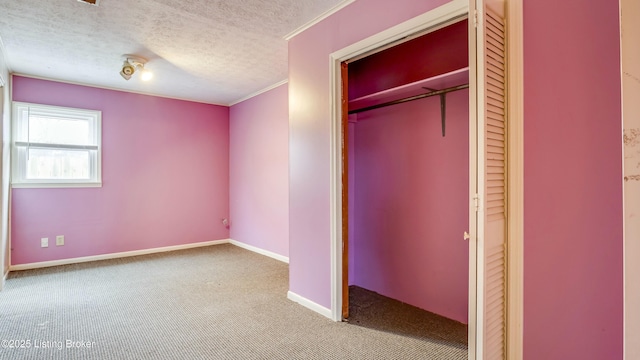 unfurnished bedroom featuring light carpet, baseboards, crown molding, a textured ceiling, and a closet