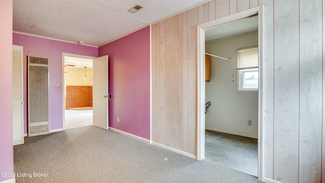 unfurnished bedroom with ornamental molding, light colored carpet, a heating unit, and visible vents