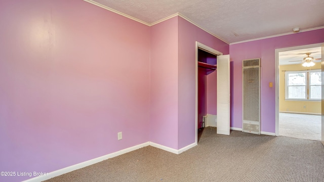 unfurnished bedroom with baseboards, ornamental molding, a textured ceiling, carpet floors, and a closet